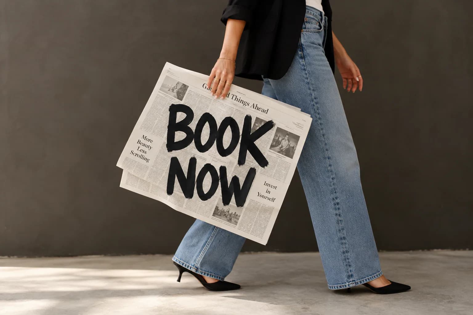 A person walking with a newspaper that reads Book Now